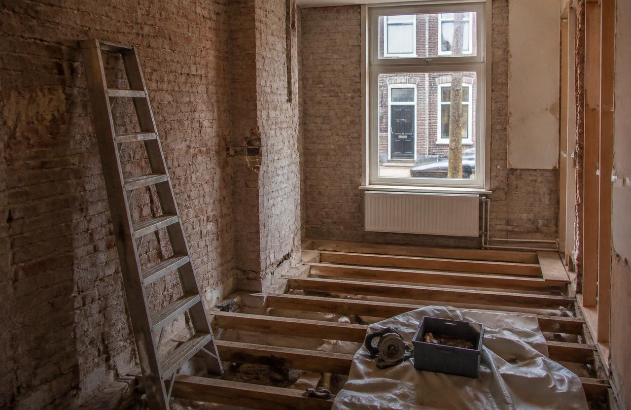 Gestripte woning in renovatie met blootliggende vloerbalken en ladder
